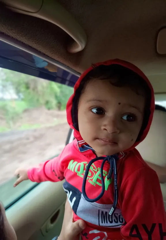 a small child wearing a red hoodie in the back of a car