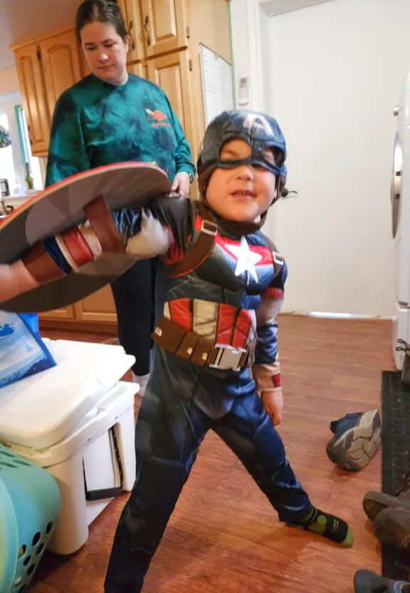 a young boy dressed as captain america holding a skateboard