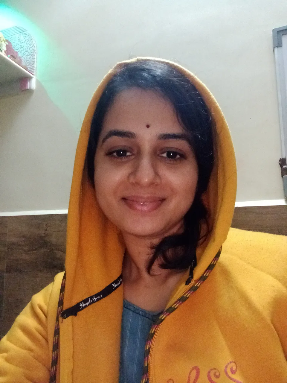 a woman in a yellow hoodie smiling for the camera