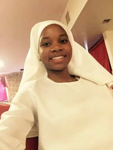 a woman wearing a white dress and a white nation of islam mgt head scarf