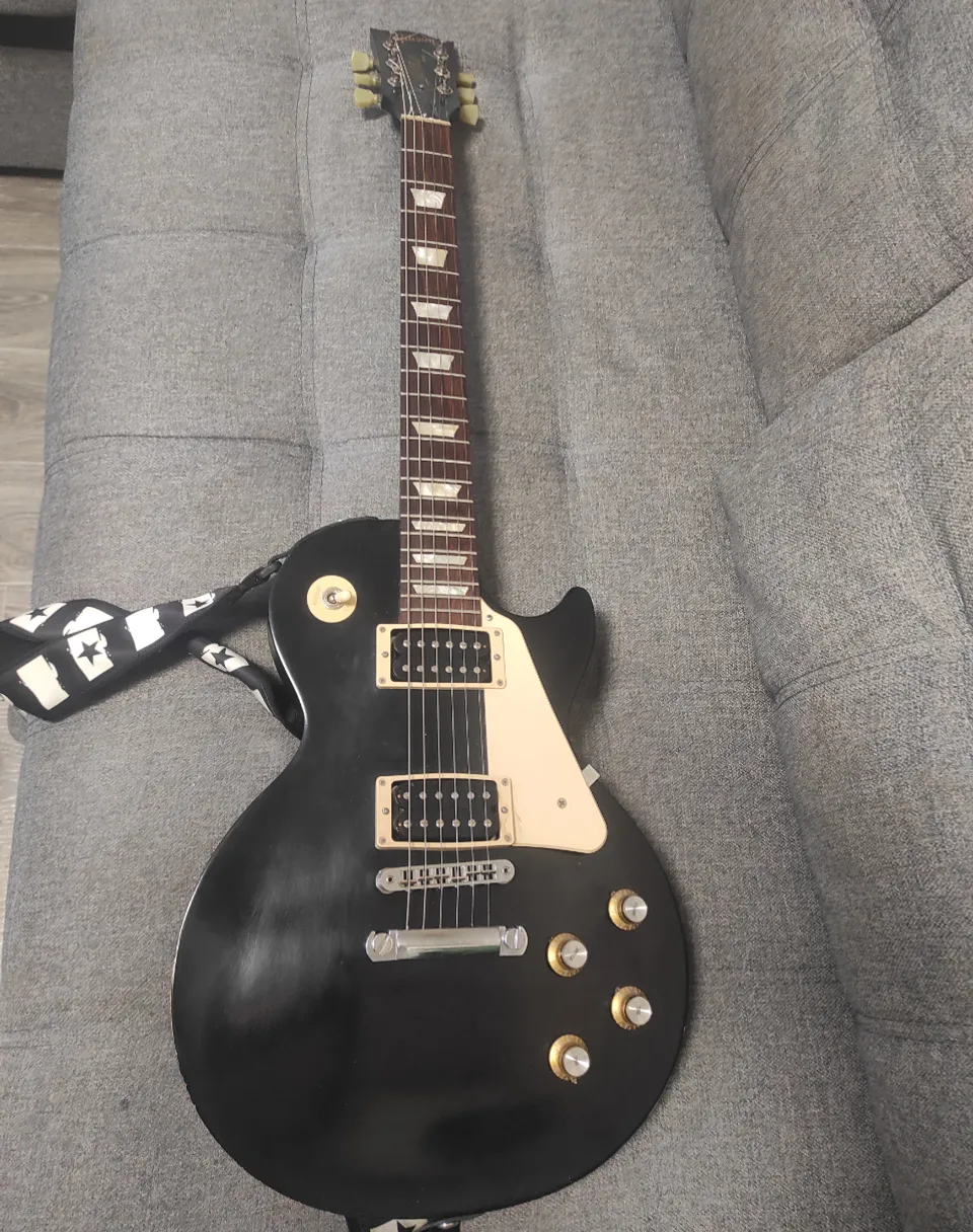 a black guitar sitting on top of a couch