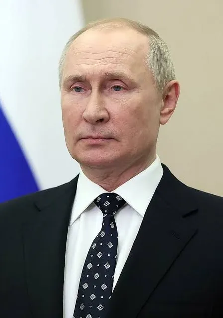 a man in a suit and tie standing in front of a flag