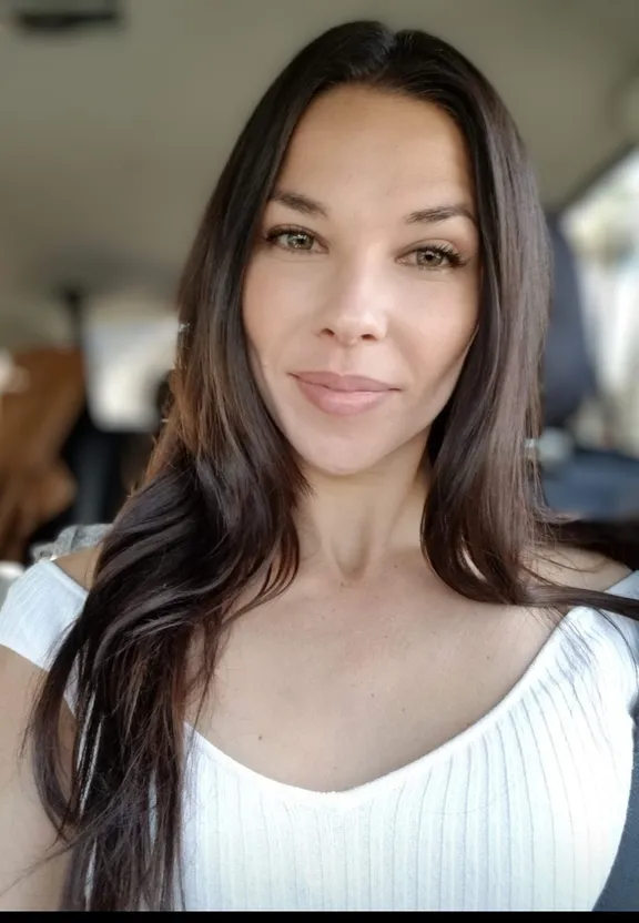 a woman in a white top is smiling for the camera