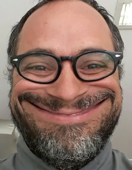 a man with a beard and glasses smiling