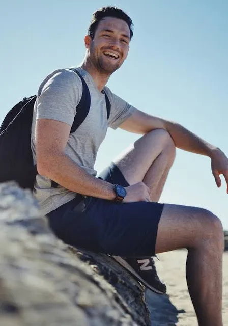 a man sitting on top of a rock near the ocean