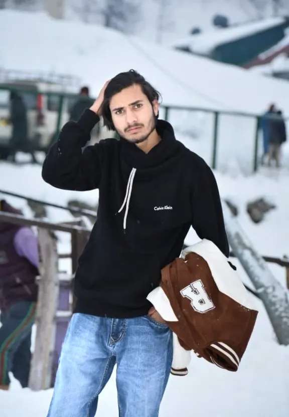 a man in a black hoodie is standing in the snow