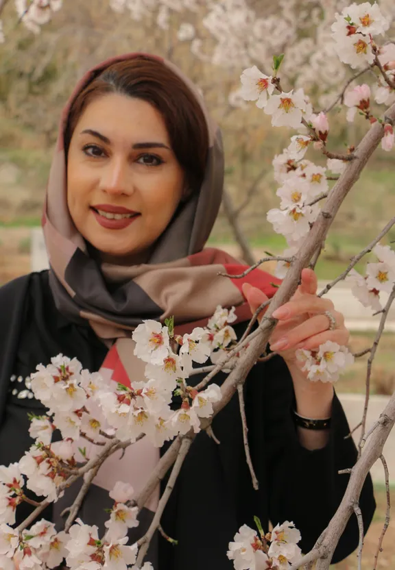 a woman wearing a headscarf and a scarf standing in front of a tree
