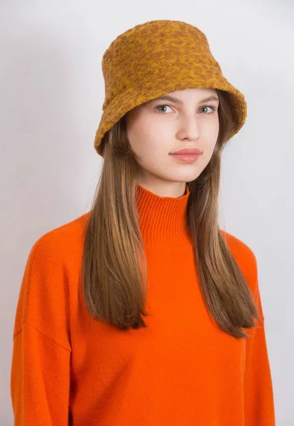 a woman wearing an orange sweater and a brown hat