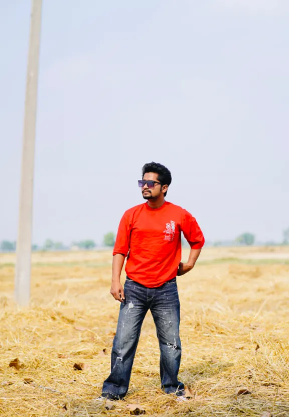 a man standing in a field next to a pole