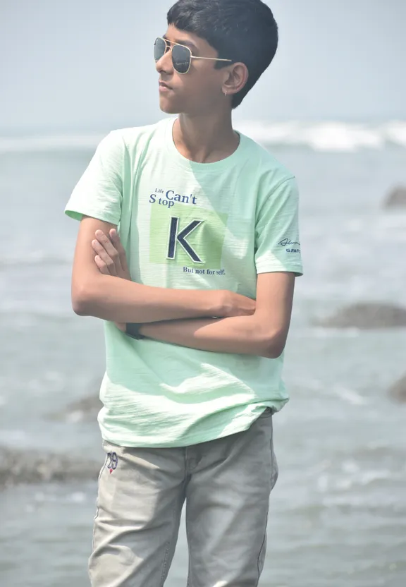 a young man standing on a beach next to the ocean