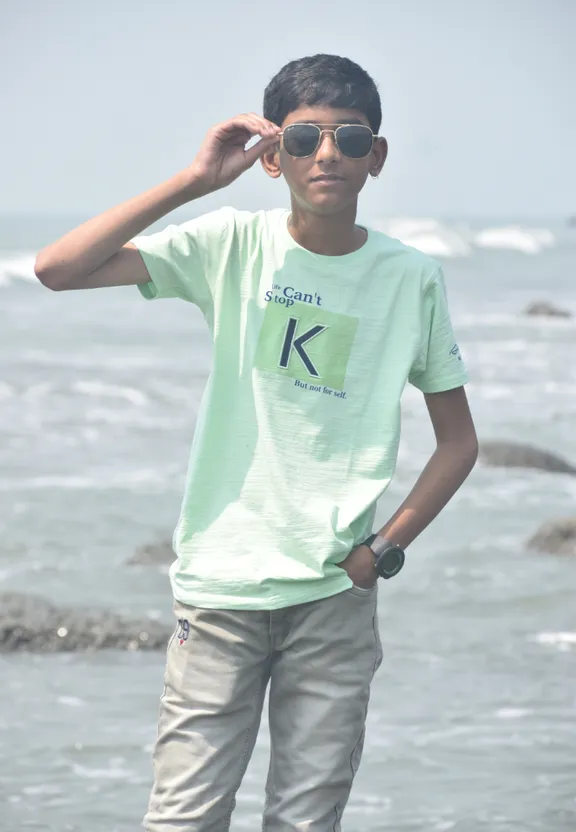 a young man standing on a beach next to the ocean