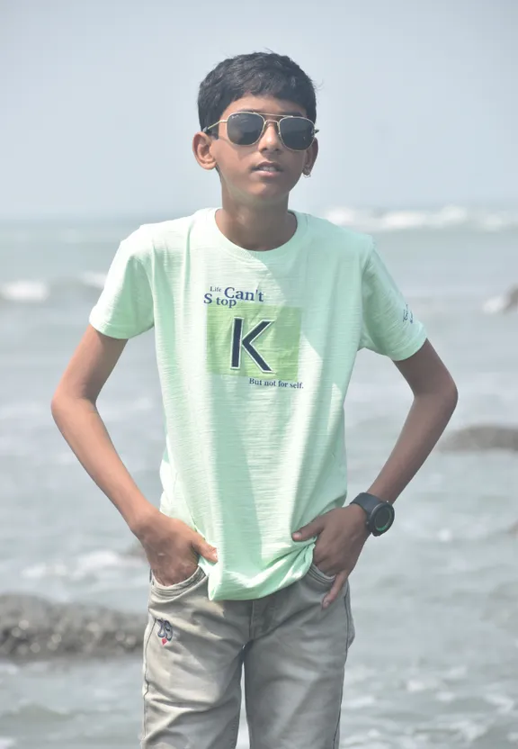 a young boy standing on a beach next to the ocean