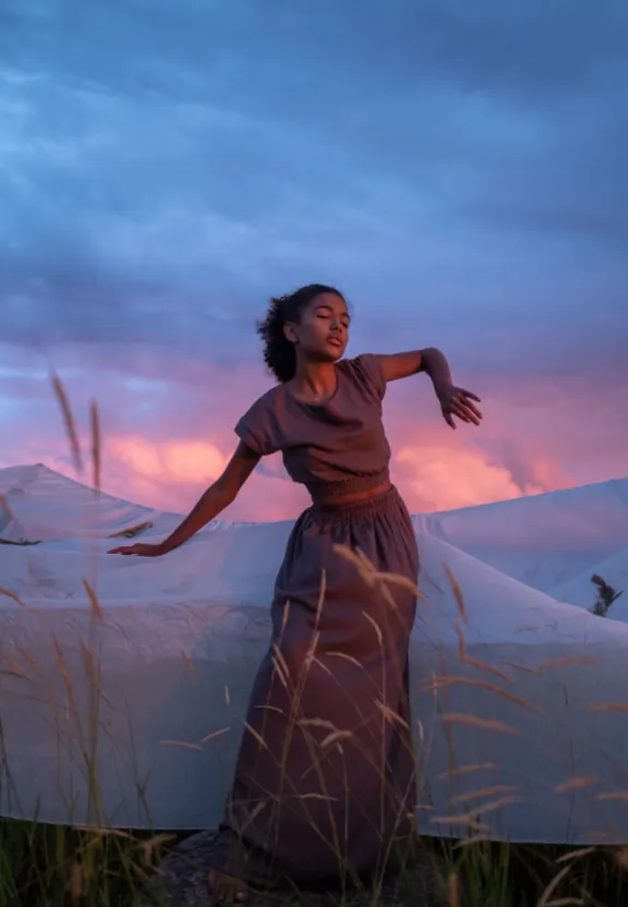 a woman standing in a field with her arms outstretched