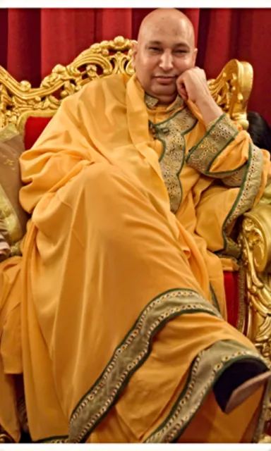 a man in a yellow robe sitting on a gold chair