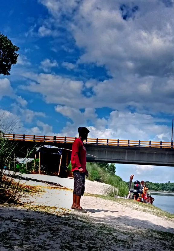 a man standing on a beach next to a bridge