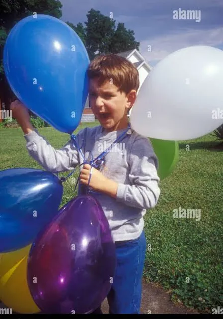 a young boy holding balloons in his hands - stock image