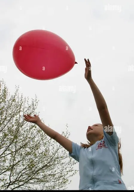 a woman reaching up to catch a frisbee in the air - stock image