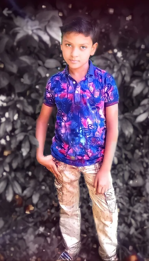 a young boy standing in front of a pile of leaves