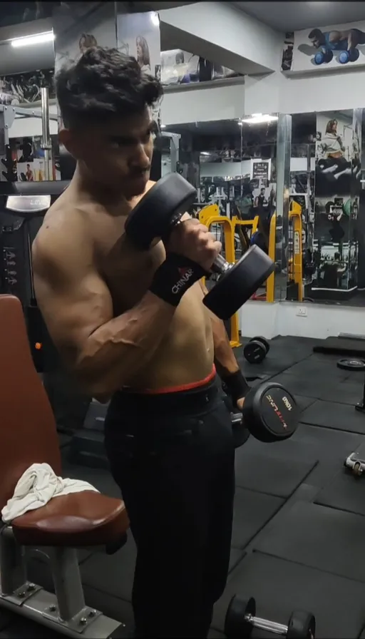 a shirtless man holding a dumbbell in a gym