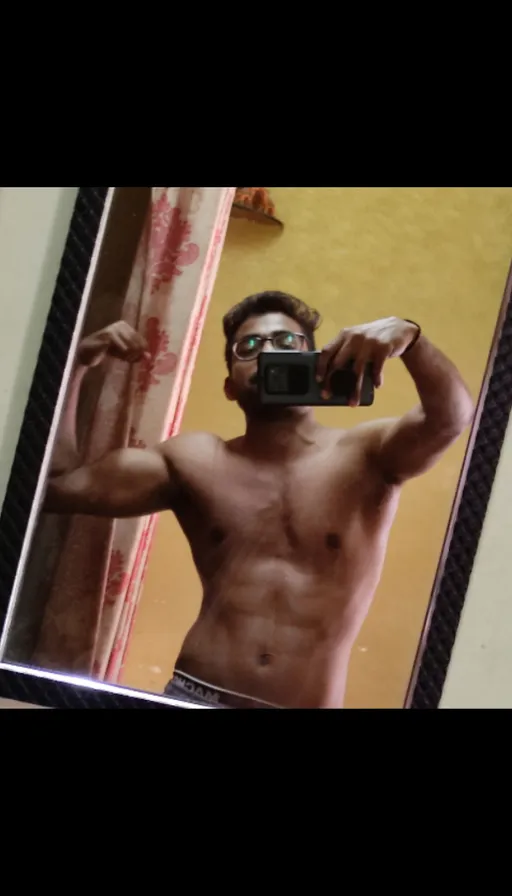 a shirtless man taking a selfie in front of a mirror