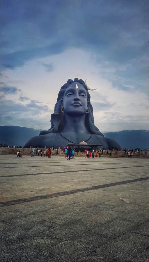 a large blue buddha statue sitting in the middle of a field