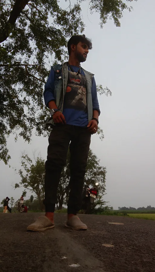 a man standing on a dirt road next to a tree