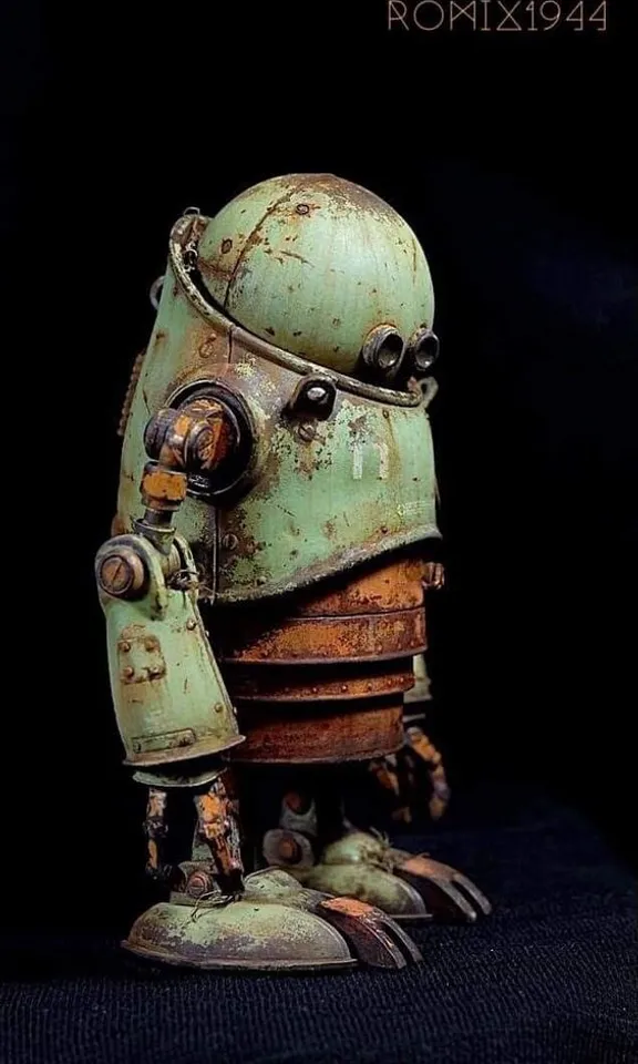 a close up of a robot statue on a black background. toy, sculpture, art, wood, machine, personal protective equipment, artifact, fictional character, metal, robot