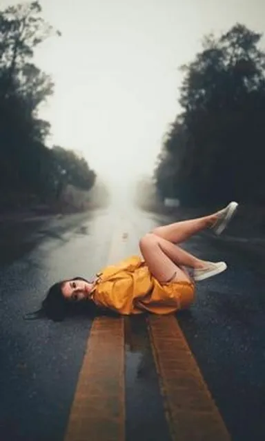 a woman laying on the side of a wet road