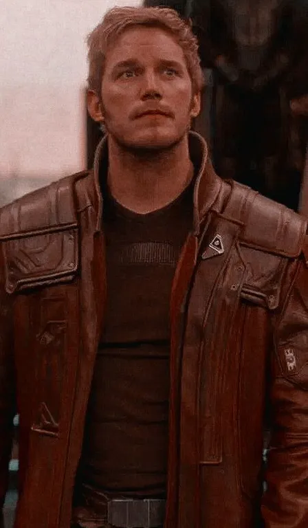 a man in a brown leather jacket standing in front of a building