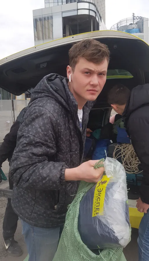 a group of people loading bags of items into the back of a bus