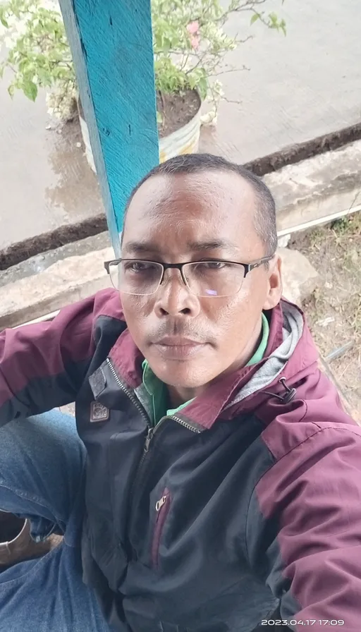 a man wearing glasses sitting on a bench