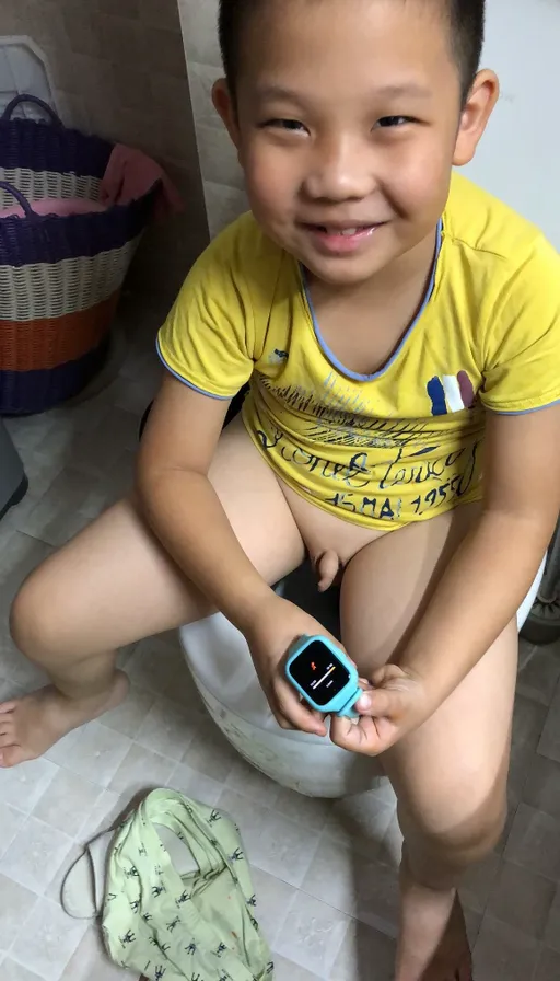 a young boy sitting on a toilet holding a cell phone