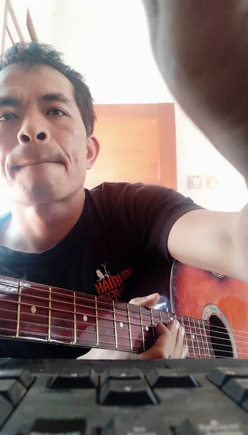 a man holding a guitar in front of a keyboard