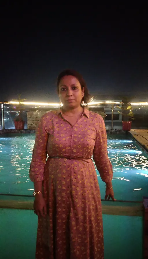 a woman standing in front of a pool at night