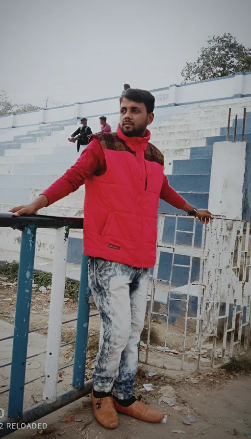 a man in a red jacket leaning on a rail