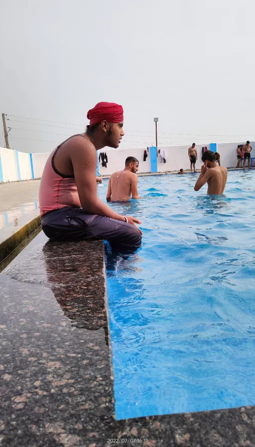 a man sitting on the edge of a swimming pool