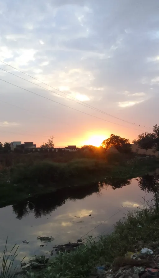 the sun is setting over a small river