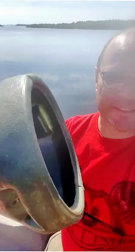 a man in a red shirt holding a large metal object