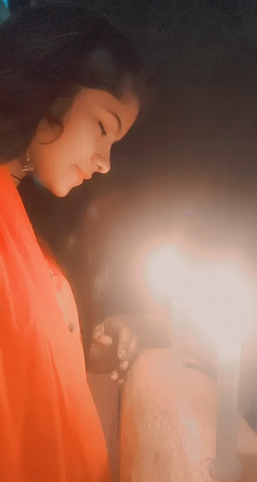 a woman in an orange dress holding a lit candle