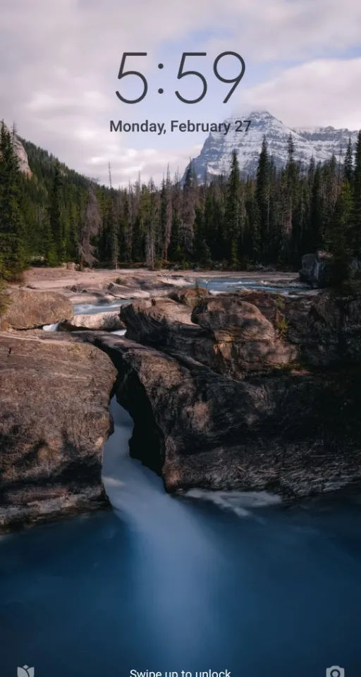 a picture of a river with a bridge and mountains in the background