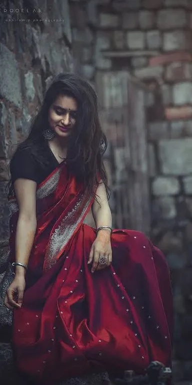 a woman in a red sari sitting on a rock