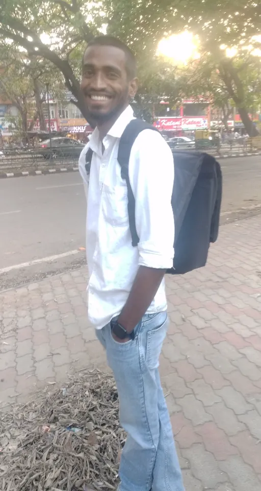 a man standing on a sidewalk with a backpack on his back