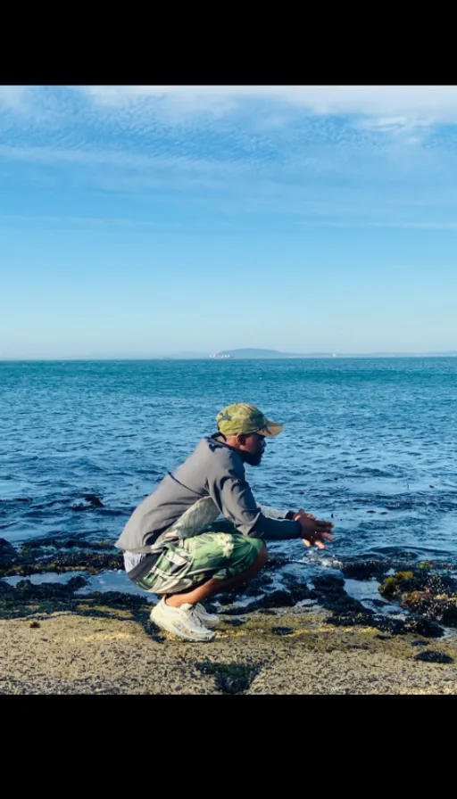 a man kneeling on a rock near the ocean