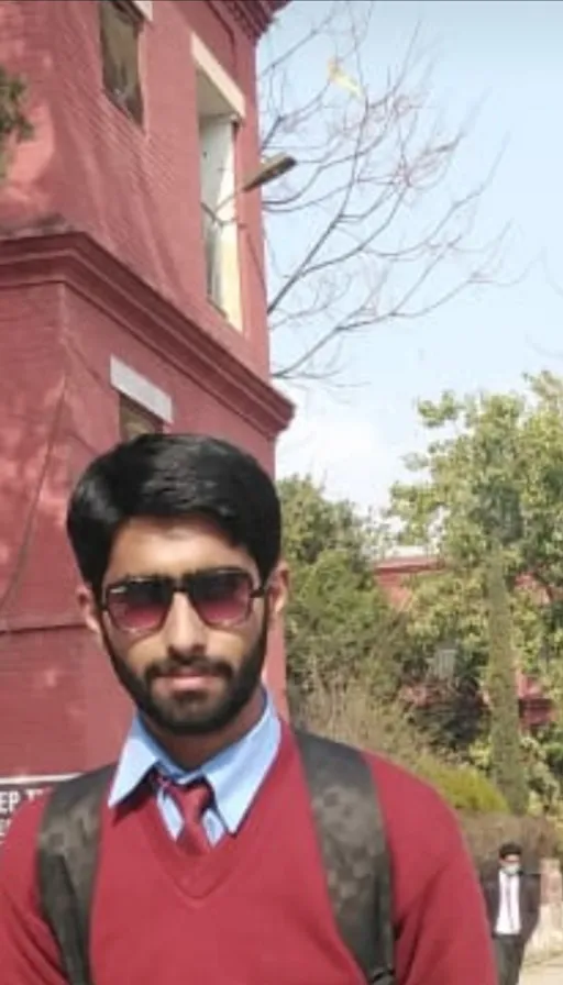 a man in a red sweater and tie standing in front of a building