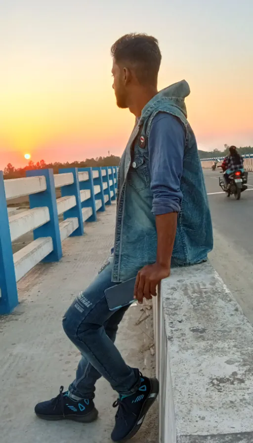 a man leaning against a wall on the side of a road