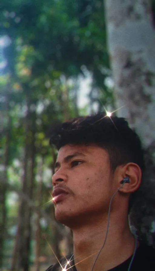 a man wearing ear buds standing in a forest