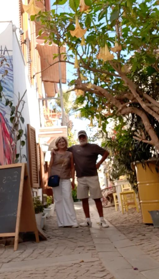 a man and a woman walking down a sidewalk. shorts, easel, building, temple, wood, plant, neighbourhood, leisure, travel, tree