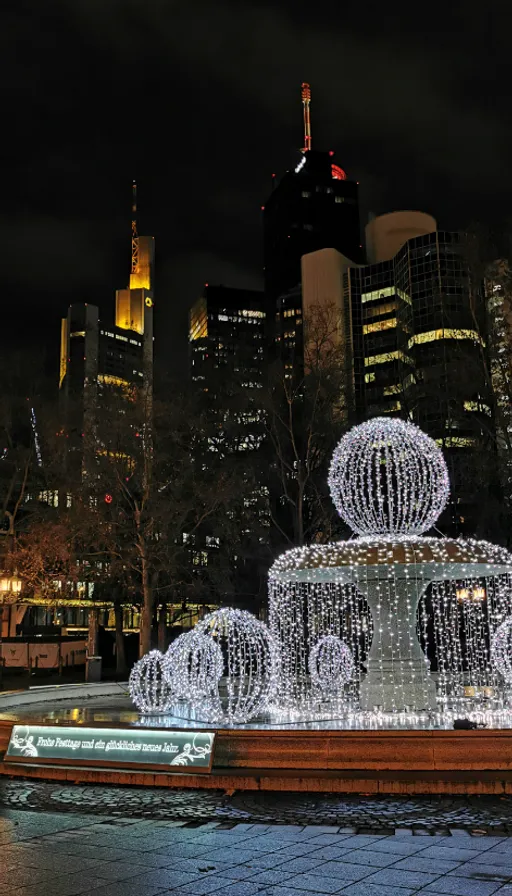 a lighted fountain in the middle of a city at night