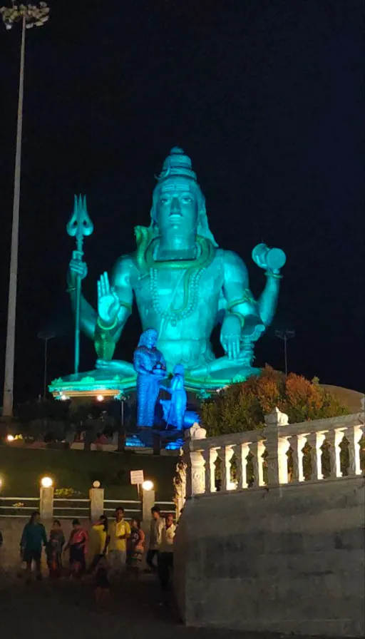 a large statue of a god is lit up at night