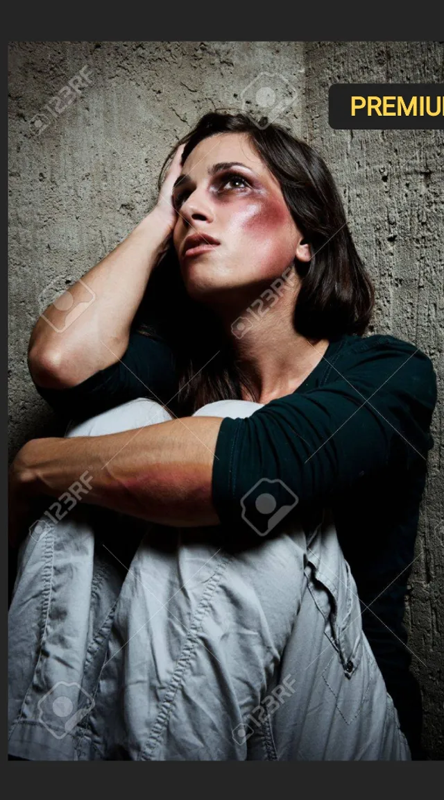 a woman with hurt on her face sitting in front of a wall